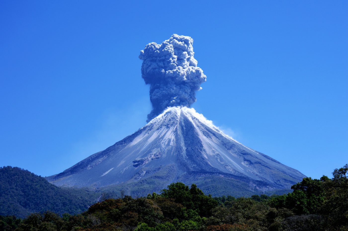 The Volcán de Colima erupting under a clear blue sky
